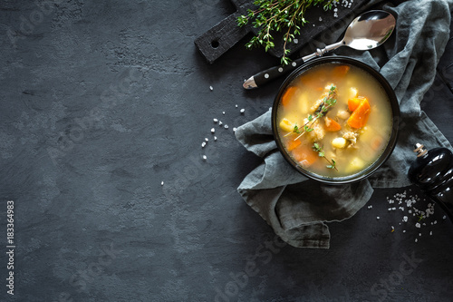 Cuadros en Lienzo Fresh fish soup in bowl on dark background, top view