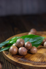 Sticker - Fresh and ripe macadamiya nuts on the wooden board.