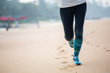 Wall Mural - Woman is jogging along the seashore on an overcast day