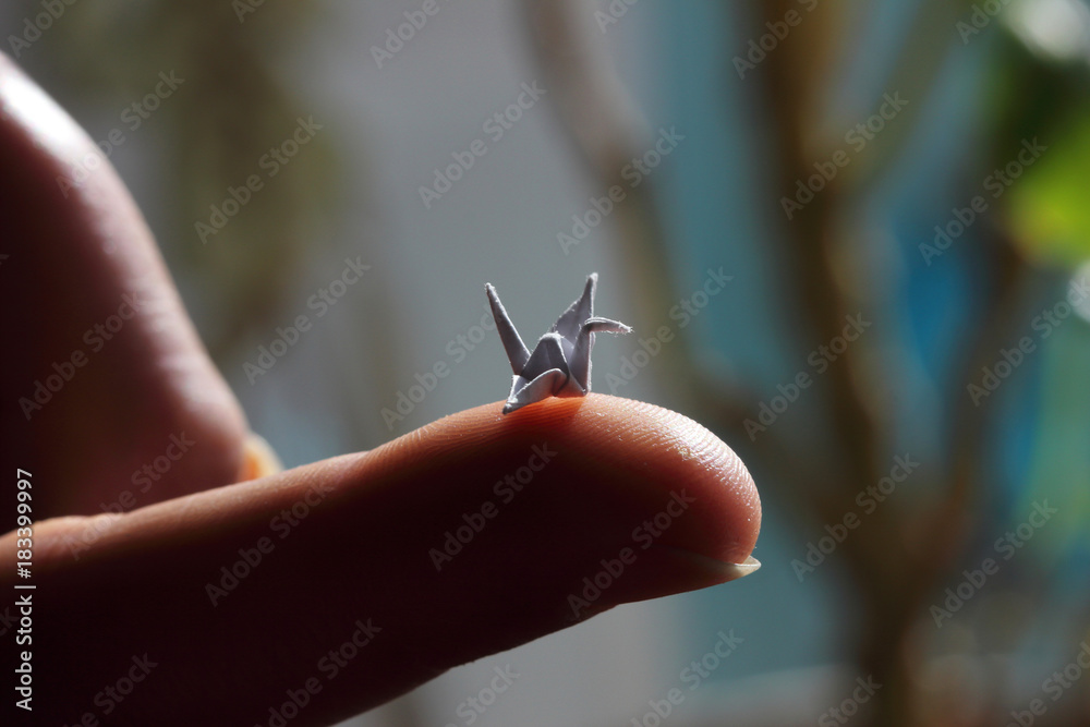 Miniature origami bird on the finger. - obrazy, fototapety, plakaty 