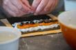 Making sushi roll with salmon, rice, olives and nori. closeup