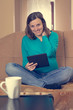 © anzebizjan - Expecting mother sitting, reading a tablet and smiling.