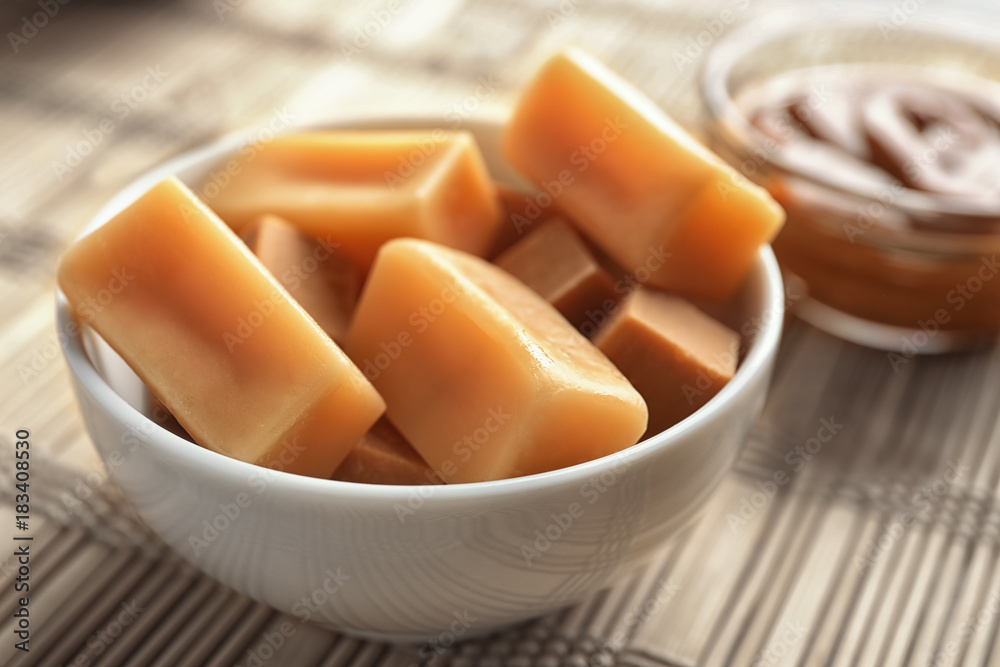 Delicious caramel candies in bowl on table
