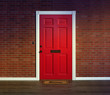 Bright red front door and welcome mat with wood porch floor.