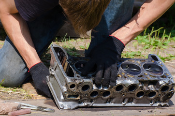 Mechanic in black working gloves repair and check part of car engine in summer outdoors