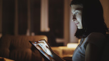 Close-up of young woman surfing tablet computer at night at home