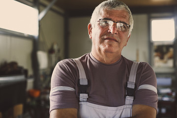 Senior Man in his workshop. Looking at camera.