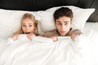 © Drobot Dean - Portrait of shocked couple lying in bed and cover with blanket