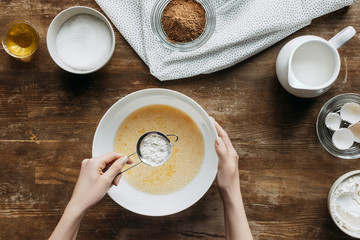 Wall Mural - cropped shot of woman preparing ingredients for baking pancakes with sieve of flour in hand