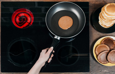 Wall Mural - cropped shot of woman frying delicious chocolate pancakes