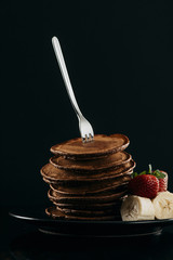 Wall Mural - delicious stacked pancakes pierced with fork on black