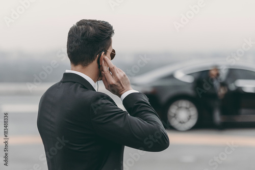 Fotografía handsome bodyguard standing and listening message with security earpiece on heli
