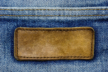 blank brown leather label on vintage blue jeans. suitable for backgrounds, articles about fashion cl