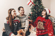 © sonyachny - merry christmas and happy new year concept. stylish hipster family in festive sweaters with cute dog tossing up gift at christmas tree lights. happy holidays.  funny emotional moments