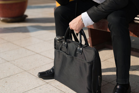 Close up, Young asian businessman hand holding Laptop bag .