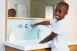 © WavebreakMediaMicro - Side view portrait of smiling boy washing hands in sink