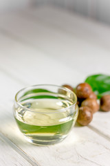 Canvas Print - Natural and organic macadamia oil on a white wooden table.