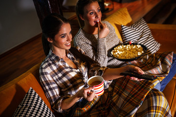 Two female best friends sitting at home on pleasant  evening and watching a movie .