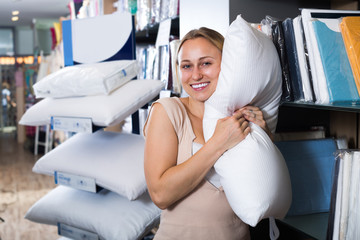 Wall Mural - Cheerful smiling woman holding downy pillow