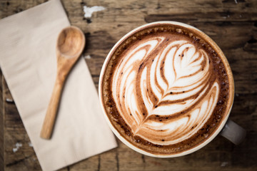 Cup of hot latte art coffee on wooden table