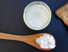 Coconut Oil In A Wooden Spoon And Glass Jar  On Dark Stone Background