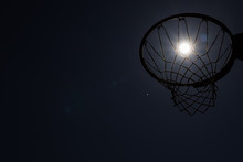 Looking Up Through Silhouetted Basketball Goal To The Moon At Night
