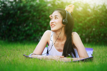 Sticker - woman listening to music with headphones and laying on a grass field