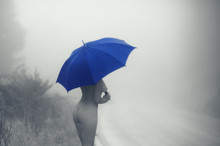 Black And White Picture Of Young  Naked Female With Blue Umbrella On The Road In The Fog. Artistic Nude Of Woman With Umbrella. 