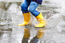 Close-up Of Kid Wearing Yellow Rain Boots And Walking During Sleet, Rain And Snow On Cold Day