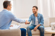 © Viacheslav Yakobchuk - Nice session. Attractive confident male patient saying goodbye to doctor while sitting on the couch and smiling