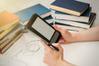 © YuSafa - A young man is reading an e-book on the background of old paper books.