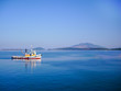 small colorful fishing boat in calm water with blue sky