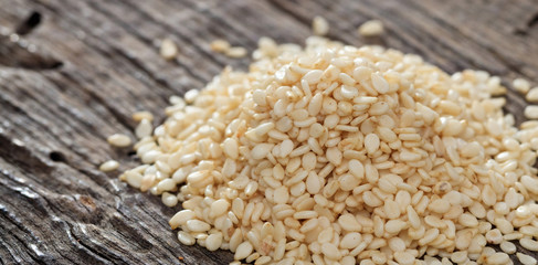 Wall Mural - A heap of raw sesame seeds, on wooden surface. Closeup view.