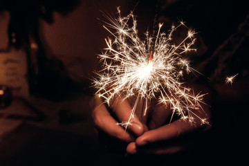 Wall Mural - happy new year and merry christmas concept. female hand holding a burning sparkler bengal light. space for text. pyrotechnics concept,  shining fire flame fireworks