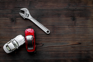 Car repair concept. Wrench near car toys on dark wooden background top view copyspace