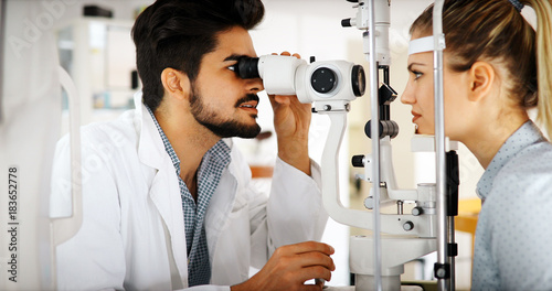 Cuadros en Lienzo Attentive optometrist examining female patient on slit lamp