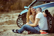 Man And Woman In White T-shirts And Jeans Hug Each Other And Laughing Sitting Near In The Mercedes Car. Passionate Young Couple.