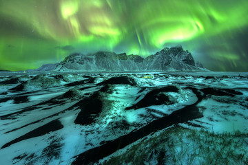 a beautiful green and red aurora dancing over the vestrahorn, iceland