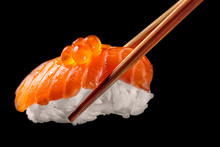 Salmon Sushi Nigiri In Chopsticks Isolated On Black Background.Close Up.