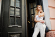 © AS Photo Family - Stylish curly blonde model girl wear on white posing against old wooden door.