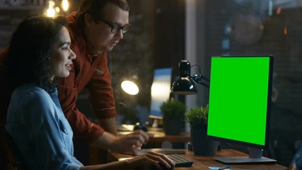 Poster - Beautiful Female Office Employee at Her Desk Talks with Her Male Coworker while Working on Mock-up Green Screen Computer. Creative Evening Office. RED EPIC-W 8K Camera.