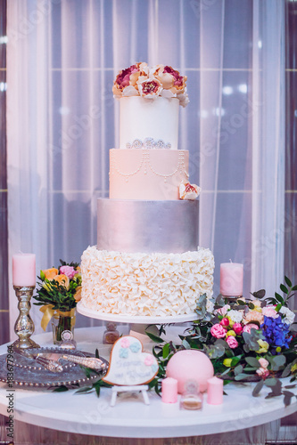 White Wedding Cake Decorated By Flowers Standing On Festive Table