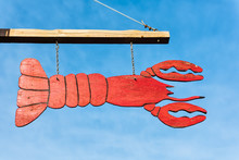 Closeup Of Red Lobster Sign For Restaurant Hanging Outside Isolated Against Blue Sky