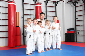 Wall Mural - Male karate instructor with little children in dojo