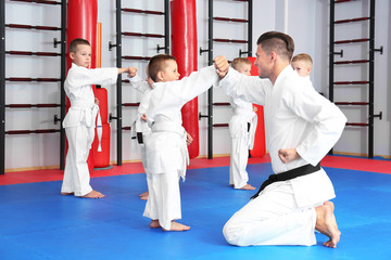 Wall Mural - Male karate instructor training little children in dojo