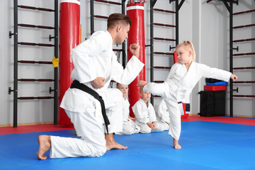 Wall Mural - Male karate instructor training little children in dojo