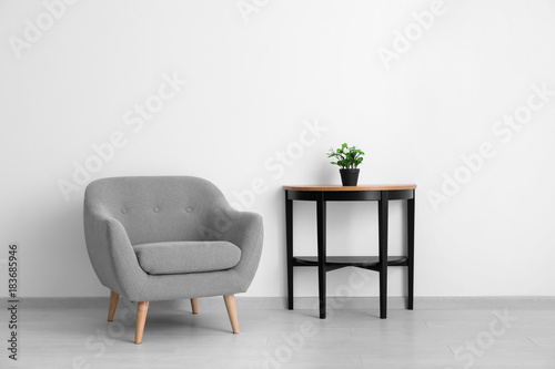 Cuadros en Lienzo Comfortable armchair and table near light wall