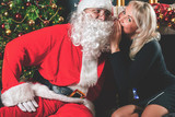Fototapeta Panele - Santa and woman near the decorated Christmas tree. Wishes list