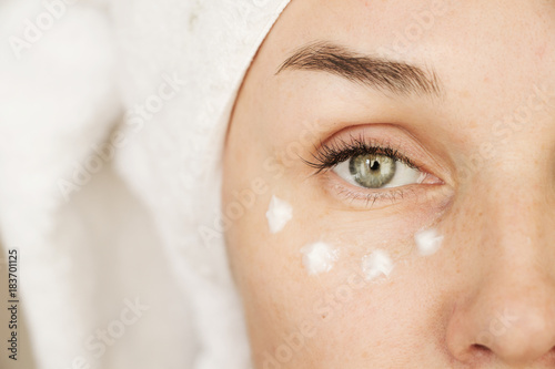 Fotografía a woman with wrinkles of forty-five years puts cream on her face