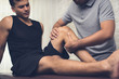 Therapist treating injured knee of athlete male patient in clinic
